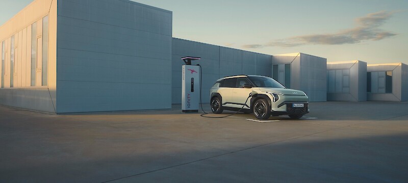 Kia EV3 töltődik az épület mellett